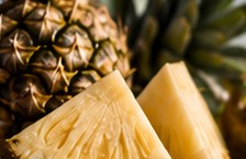 Cut pineapple beside the whole fruit.
